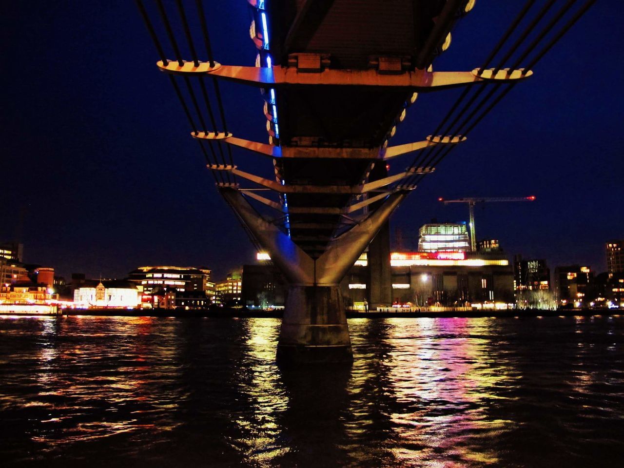 ILLUMINATED BRIDGE OVER RIVER AT NIGHT