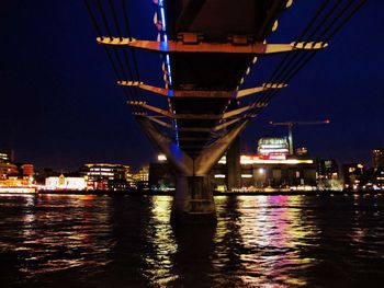 Illuminated bridge over river in city at night