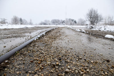 Surface level of abandoned snow covered railroad track against sky