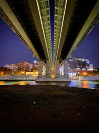 Low angle view of bridge over river at night