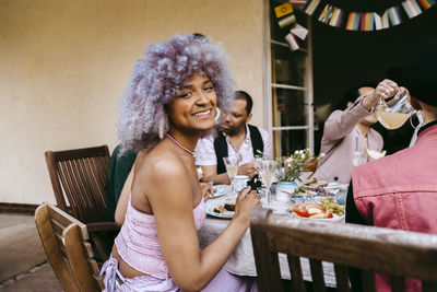 Side view portrait of happy transwoman with friends during dinner party in back yard