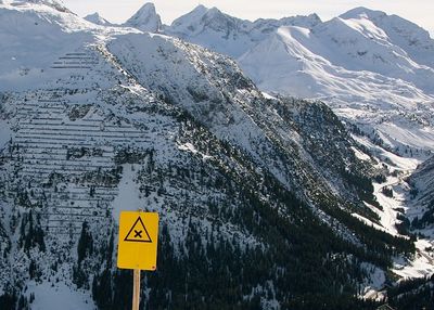 Warning sign against snowcapped mountains during winter