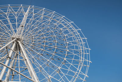 Low angle view of ferris wheel against blue sky