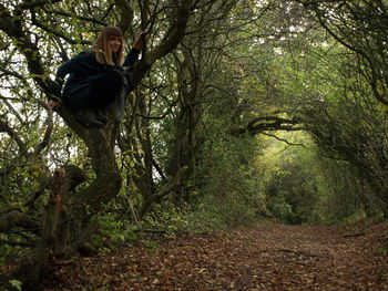 Woman sitting on tree trunk at forest