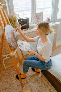 Side view of young woman sitting on table at home