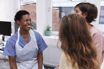 Female doctor talking to girl patient and mother during appointment