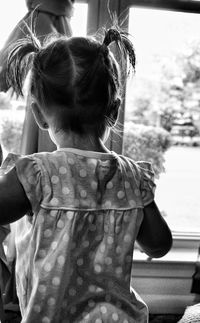 Rear view of girl with pigtails standing at home