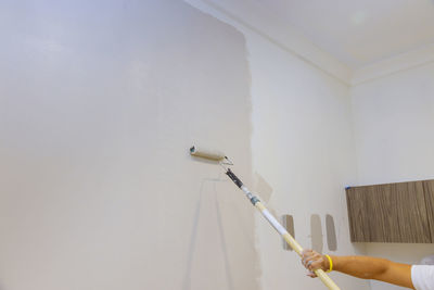 Cropped hand of man painting wall at home