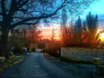 Road amidst trees against sky during sunset