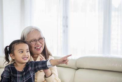 Granddaughter and grandmother looking away at home