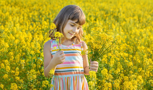 Cute girl holding flowers while standing in field