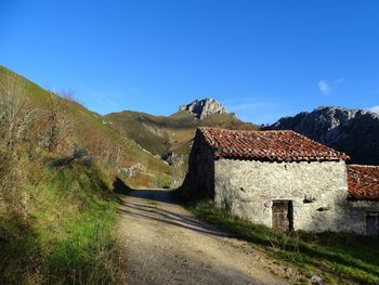 Road leading towards mountain against blue sky