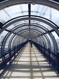 Rear view of people walking on covered footbridge