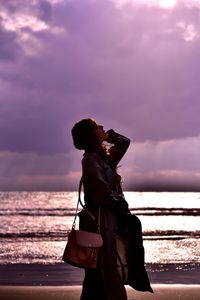 Woman standing by sea against sky