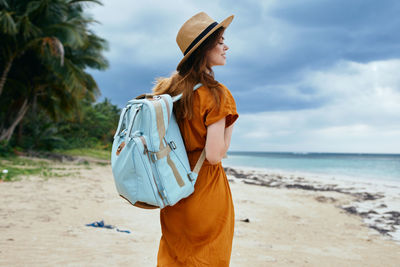 Woman standing at beach against sky