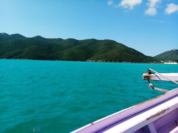 Scenic view of sea and mountains against clear blue sky