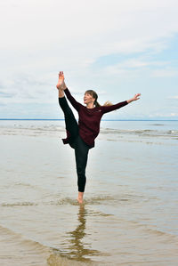 Full length of mid adult woman exercising on shore