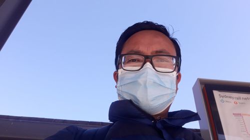 Portrait of man wearing mask standing against sky