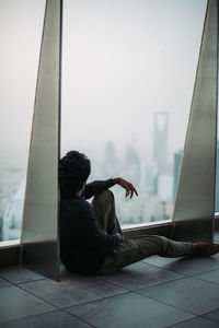 Full length of man sitting by window in building