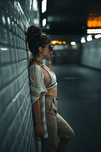 Side view of woman standing against illuminated wall