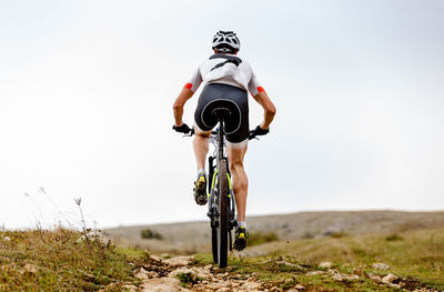 Lone male cyclist riding on mountain road in background sky