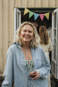 Portrait of smiling young woman holding wineglass during dinner party at cafe