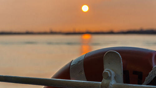 Close-up of metal railing against sea during sunset