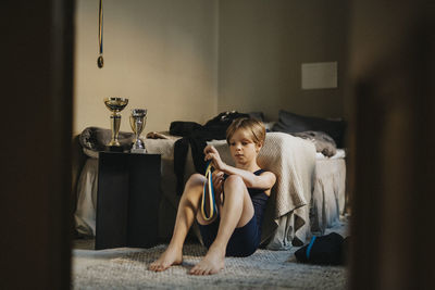 Elementary boy looking at medal while sitting in bedroom