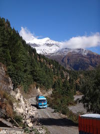Car on road by mountains against blue sky