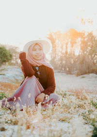 Portrait of young woman sitting on field