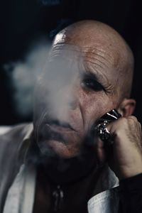 Close-up portrait of bald man smoking cigarette