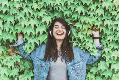 Portrait of smiling young woman standing against plants