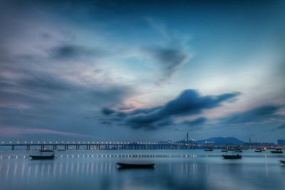 Boats moored in sea against sky at dusk