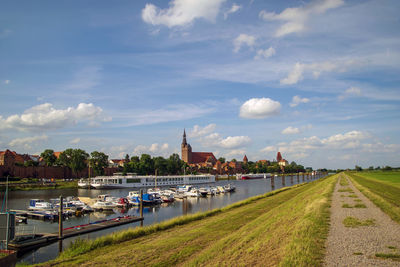 Scenic view of river by buildings against sky