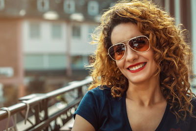 Young moroccan woman, with curly brown hair, sitting in an outdoor café in mainz, wearing sunglasses