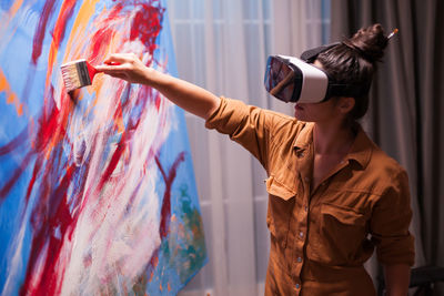 Woman painting while wearing virtual reality headset