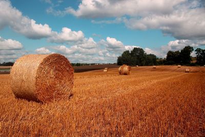 Hay bales on field against sky