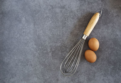 Directly above shot of eggs and wire whisk on marble