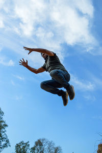 Low angle view of man jumping against sky