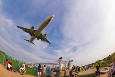 Low angle view of people at airplane against sky