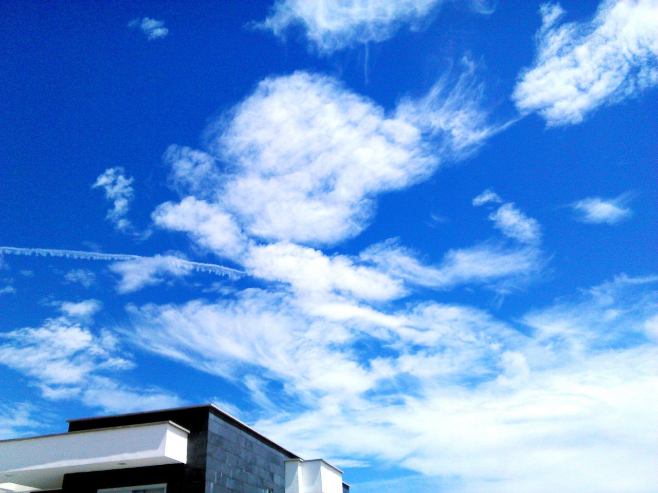 low angle view, sky, building exterior, architecture, built structure, blue, cloud - sky, cloud, high section, house, building, outdoors, cloudy, residential structure, day, no people, residential building, nature, sunlight, white color