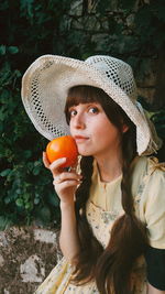 Portrait of beautiful young woman holding tomato