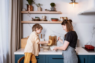Family fun in the kitchen. mother and son baking carrot cake together. scandinavian kitchen interior