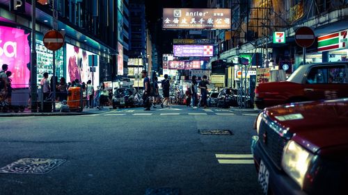 People and cars on city street at night