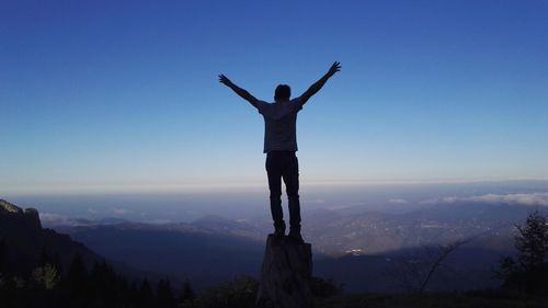 Man standing on mountain against clear blue sky