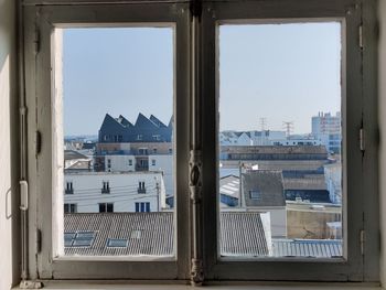 Buildings against clear sky seen through glass window