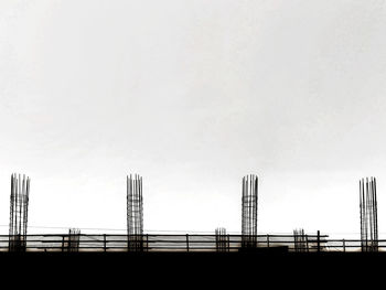 Low angle view of silhouette bridge and buildings against sky