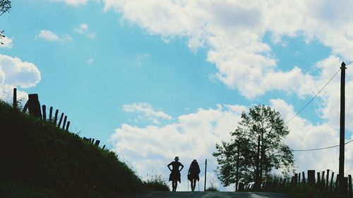 Silhouette of woman standing against cloudy sky