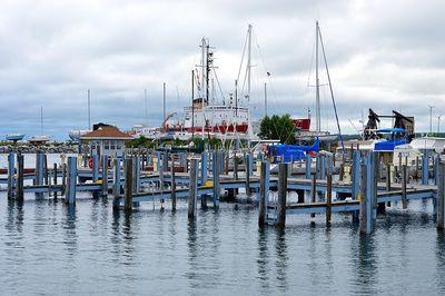 Boats moored in harbor against sky