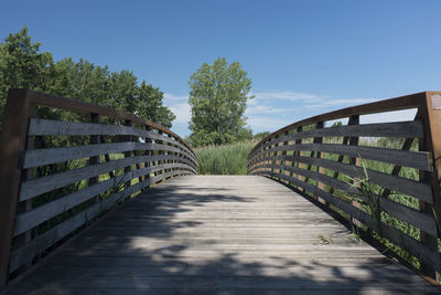 Empty footpath along railings against sky